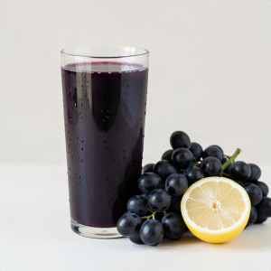 Glass of deep purple homemade black grape juice with fresh black grapes and a halved lemon