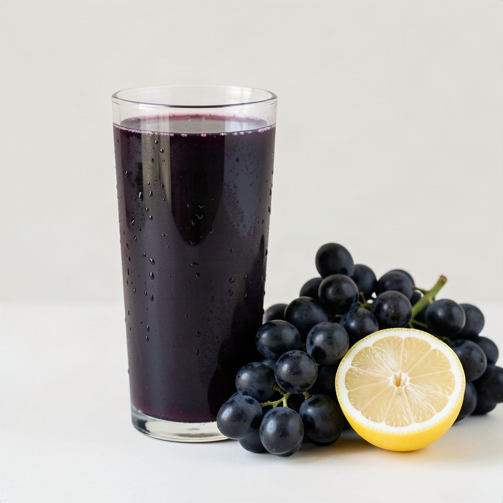 Glass of deep purple homemade black grape juice with fresh black grapes and a halved lemon